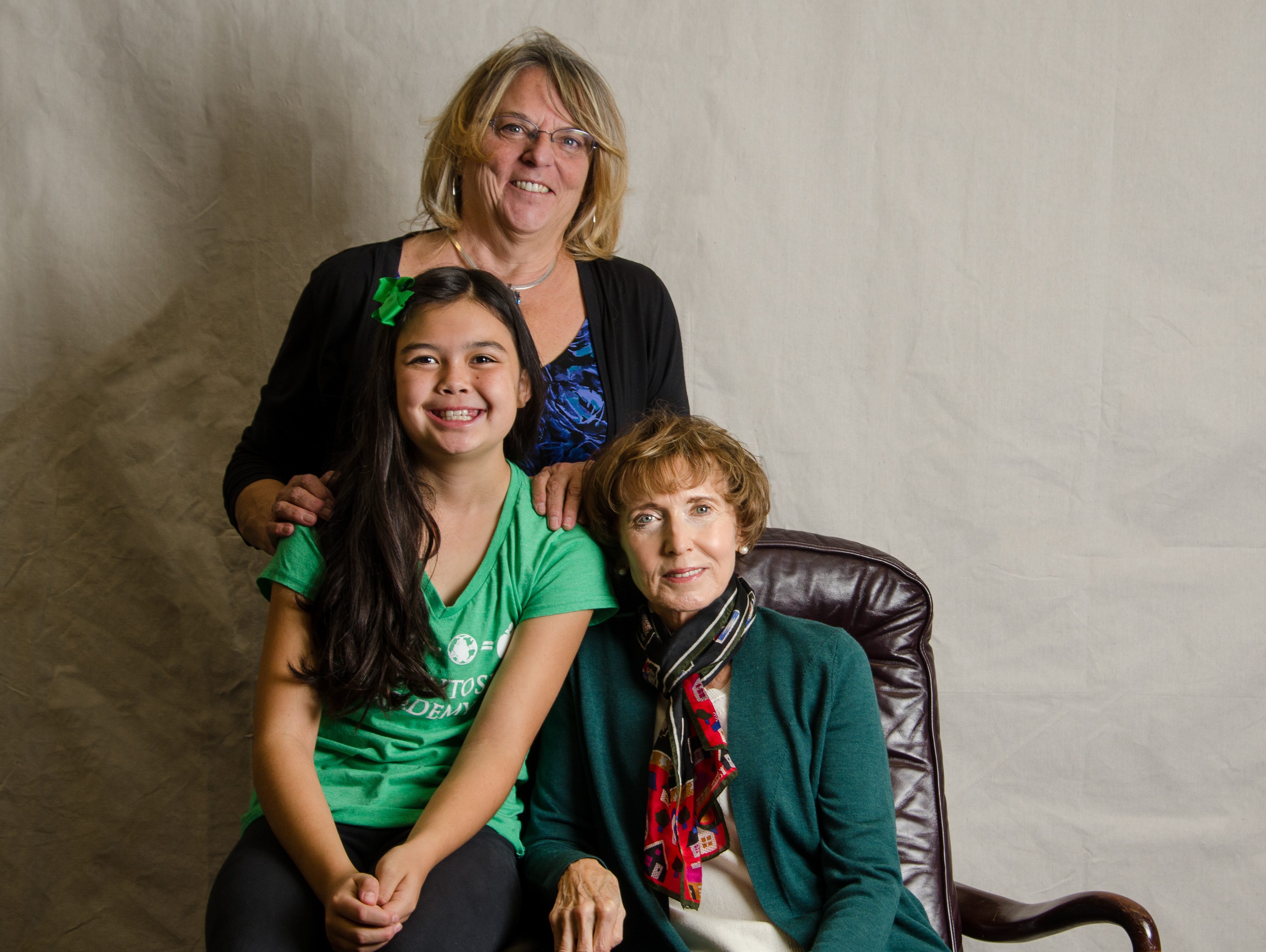 a mother standing with daughter and grandmother seated in a chair