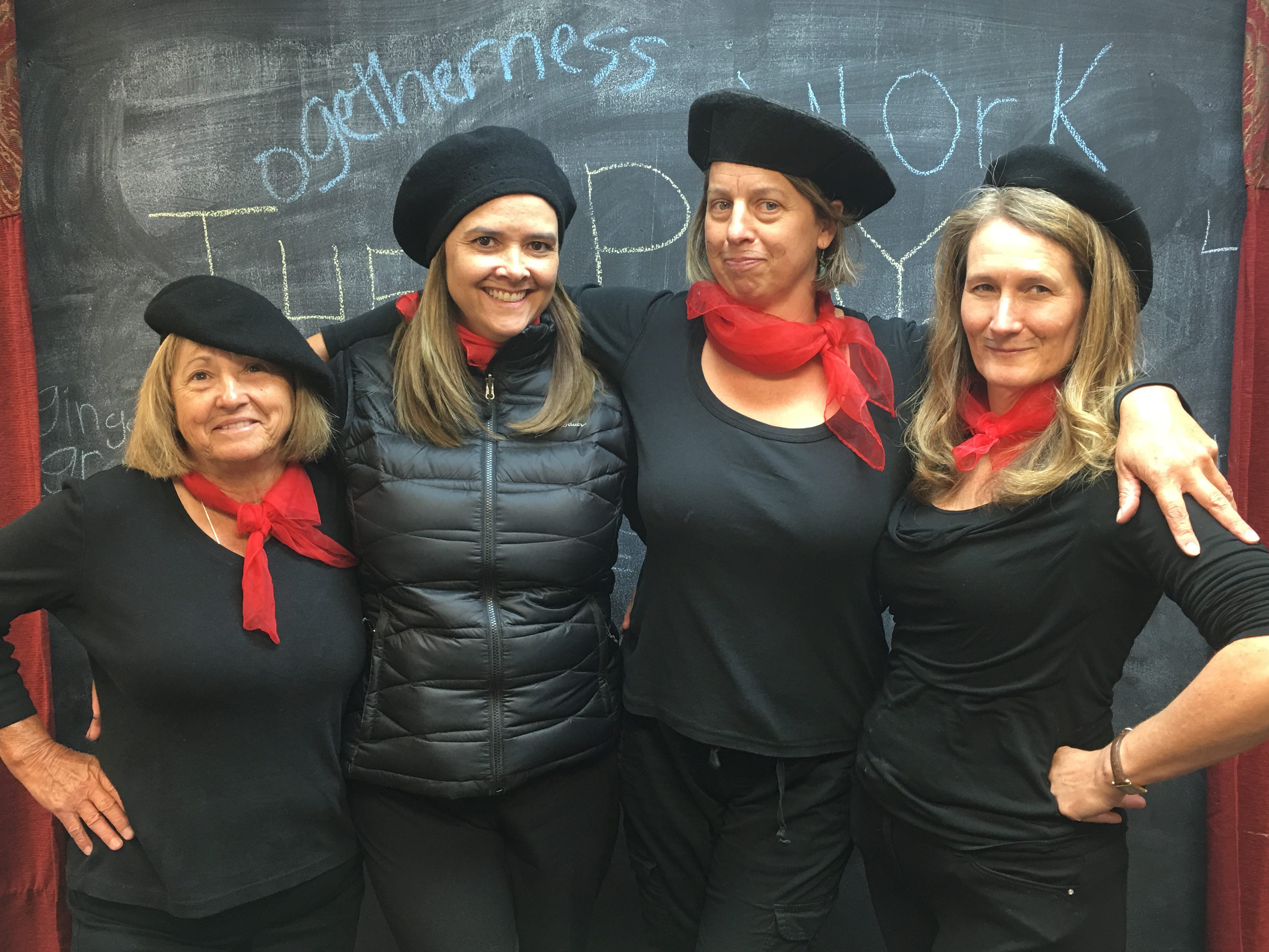 four teachers dressed in matching outfits with black berets and red scarves